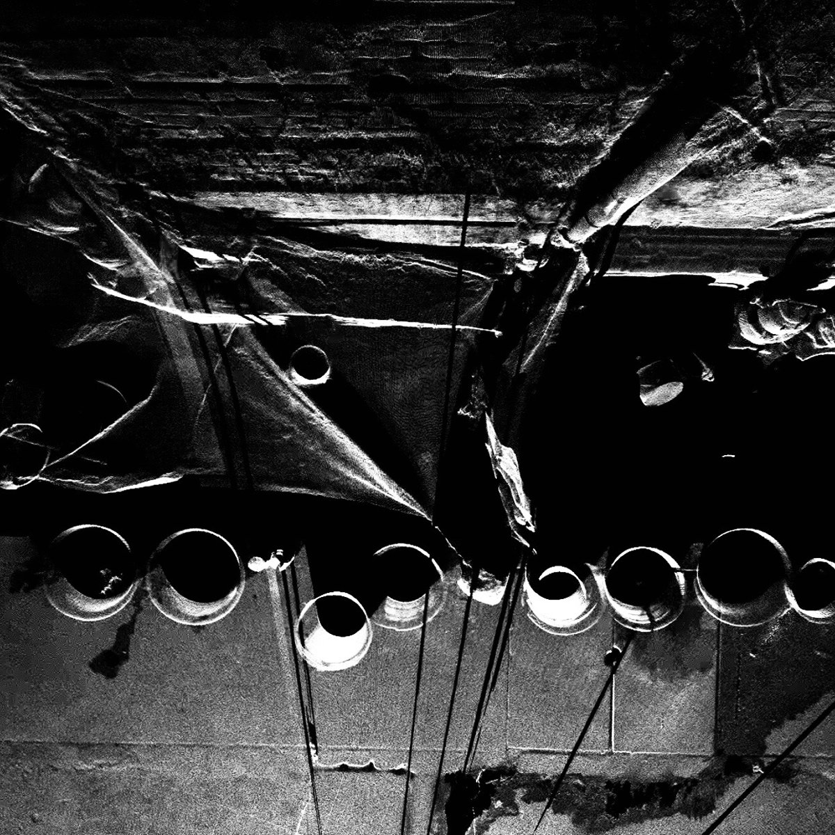 Still from Pansodan Street: black and white point cloud scan looking up at a building underside with circular openings, sheeting and hanging cables